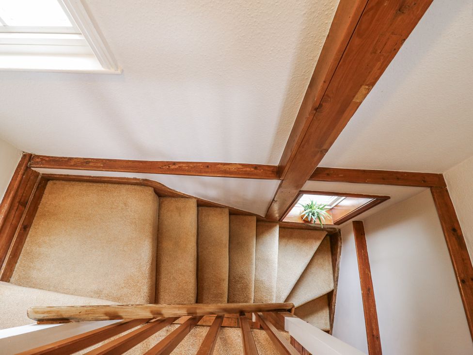 A staircase with a wooden railing and window at White Gates in Banham