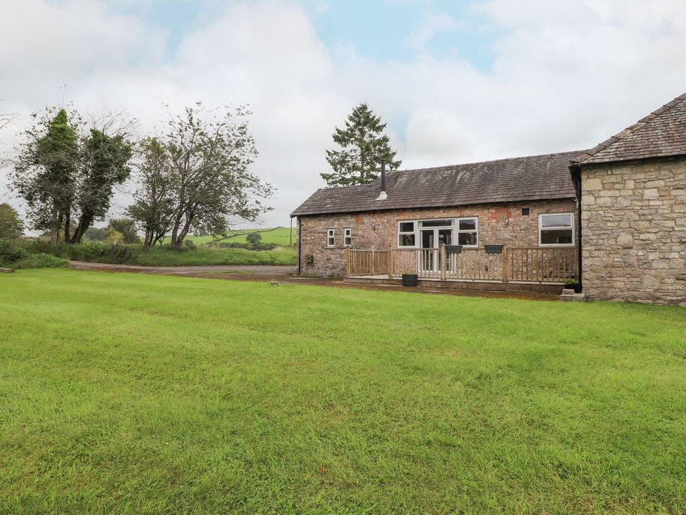 An outdoor view of a stone building with a wooden deck at The Gatehouse 