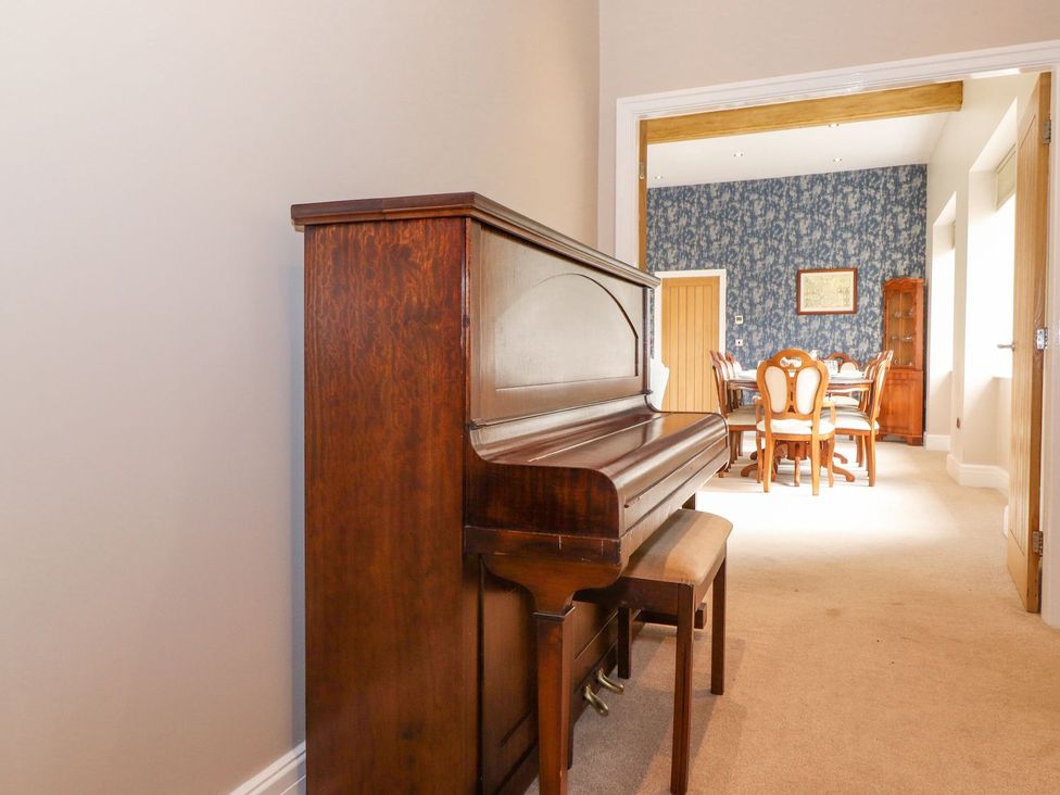 A piano and wooden stool in a dining room at The Gatehouse