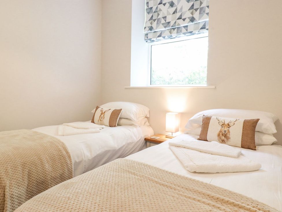 A bedroom with two beds, a lamp, and a window at The Gatehouse in 