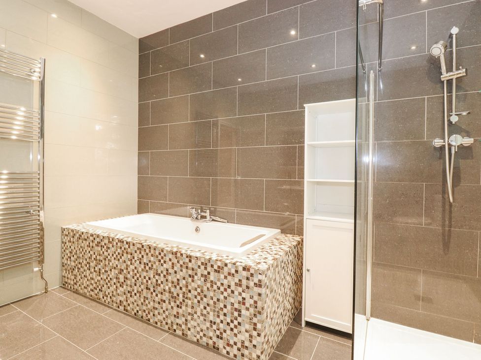 A bathroom with a bathtub and shower unit at The Gatehouse