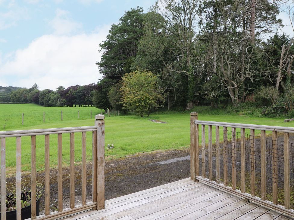 A view of a grassy area with trees from a wooden deck at The Gatehouse