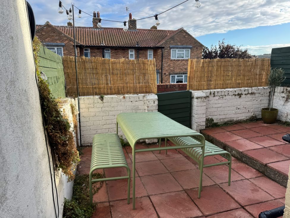 A garden with a table and benches at Launcher's Cottage in Scarborough