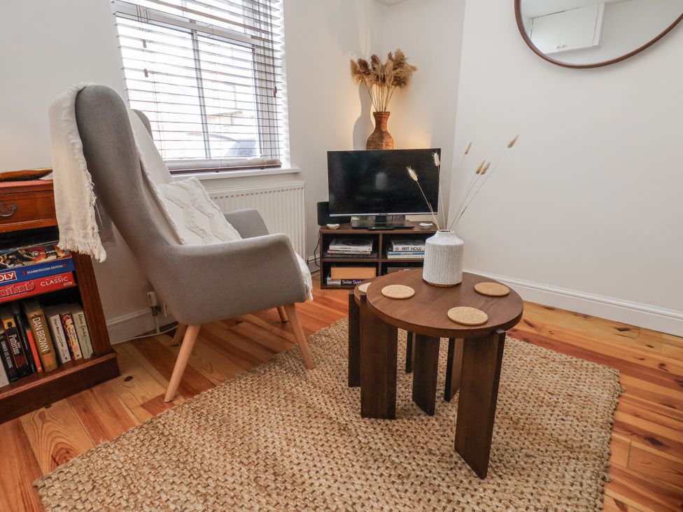 A living room with an armchair, television, and coffee table at Launcher's Cottage in Scarborough