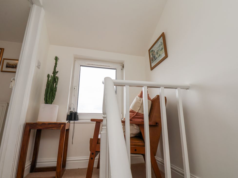 A landing area with a chair and window at Launcher's Cottage in Scarborough