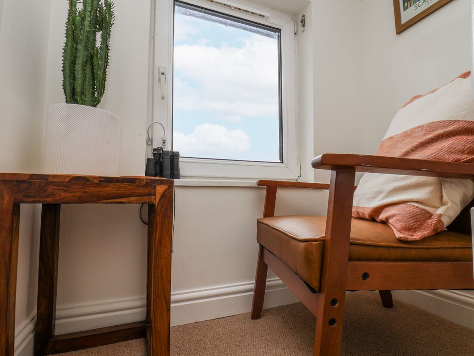 A snug area with a chair, table, plant, and binoculars at Launcher's Cottage in Scarborough