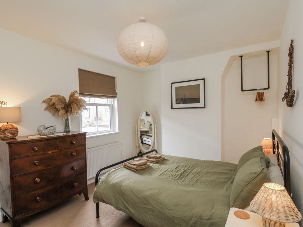 A bedroom with a bed and dresser at Launcher's Cottage in Scarborough