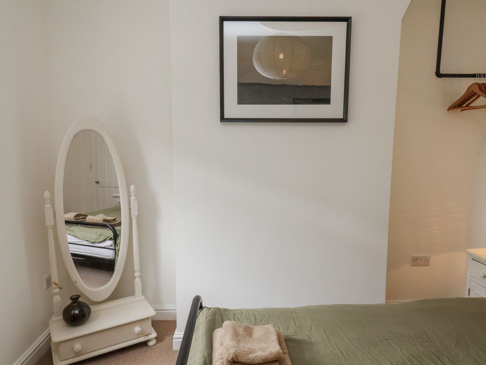 A bedroom with a bed and a mirror at Launcher's Cottage in Scarborough