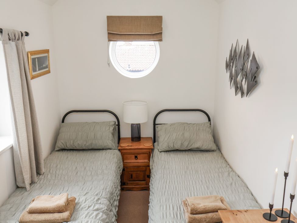 A bedroom with two beds and a window at Launcher's Cottage in Scarborough