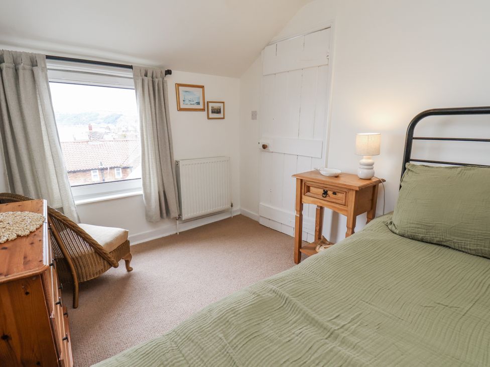 A bedroom with a bed and nightstand at Launcher's Cottage in Scarborough