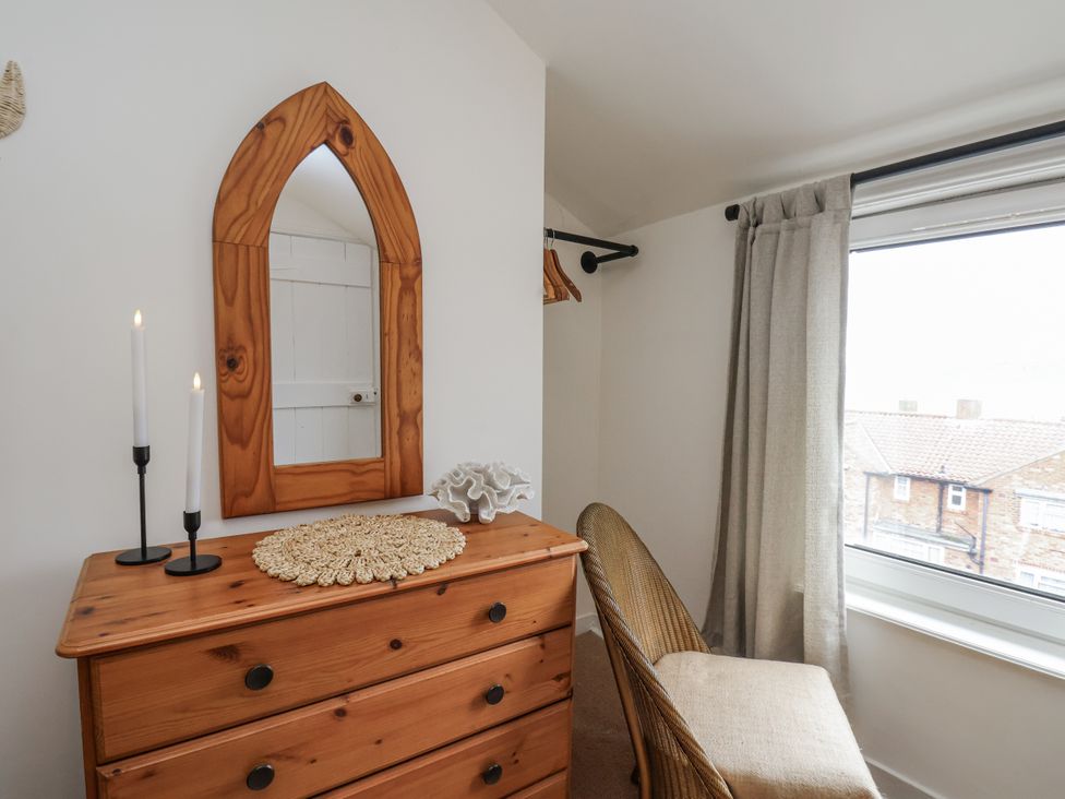 A bedroom with a dresser and mirror at Launcher's Cottage in Scarborough