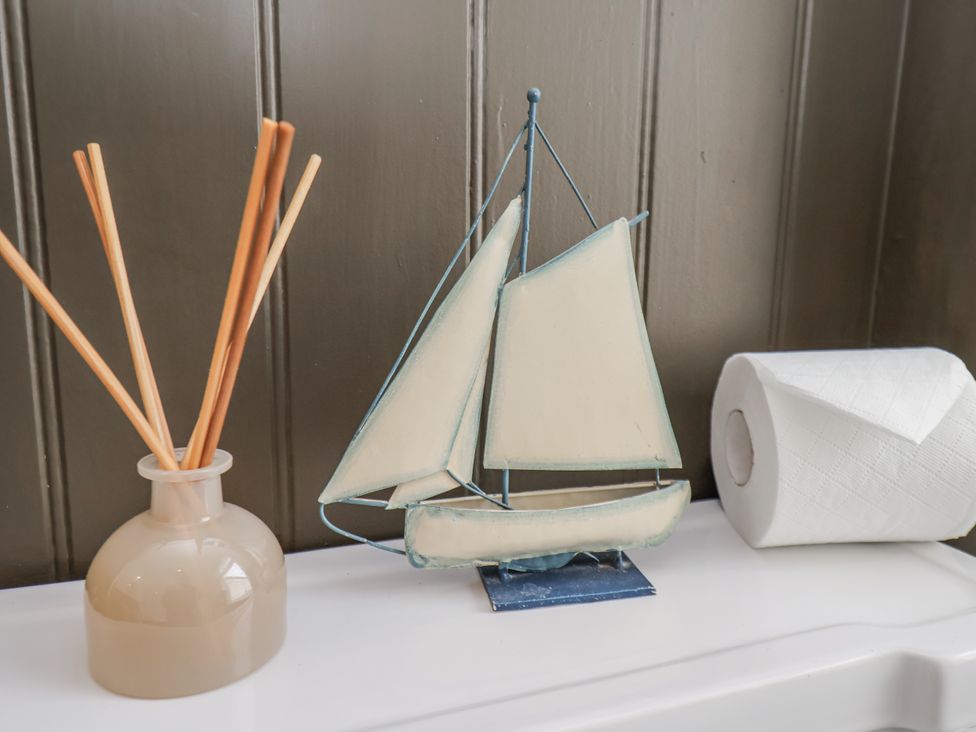 A sailboat and a vase with reed sticks in a bathroom at Launcher's Cottage in Scarborough