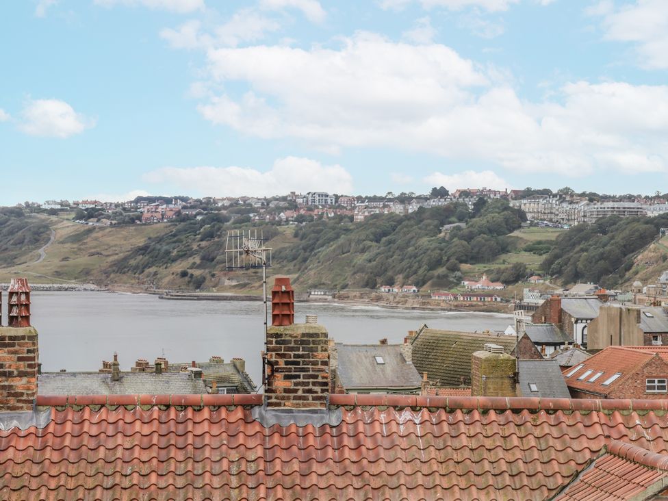 A view of rooftops and hills near the water at Launcher's Cottage in Scarborough