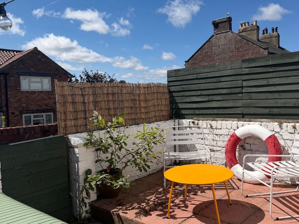 A garden with a yellow table and white chairs at Launcher's Cottage in Scarborough