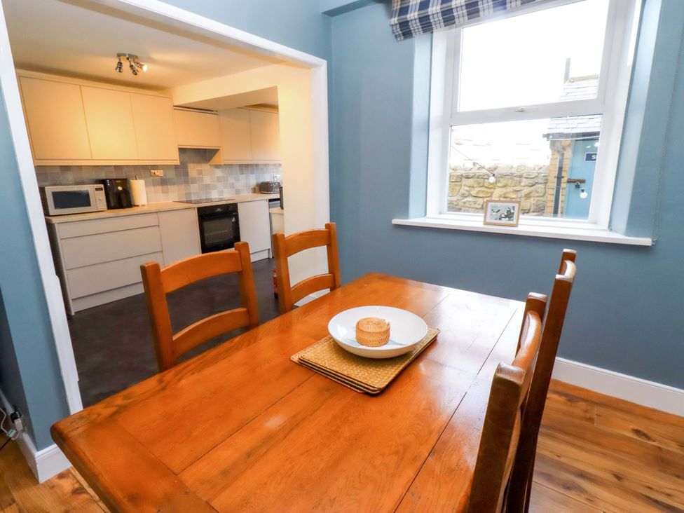 A kitchen with a wooden table and chairs at Dinguardi in Seahouses