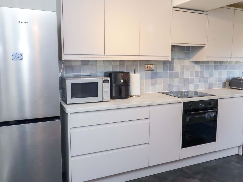 A kitchen with appliances and cabinets at Dinguardi in Seahouses