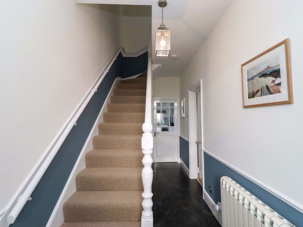 A hallway with a staircase and light fixture at Dinguardi in Seahouses