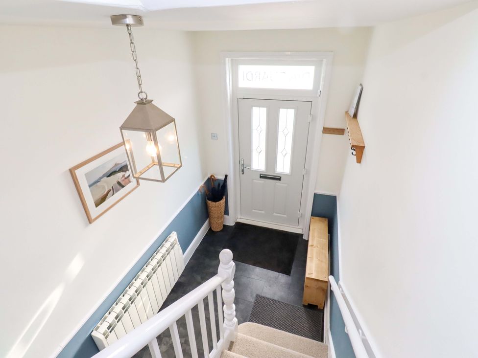 A hallway with a staircase and door at Dinguardi in Seahouses