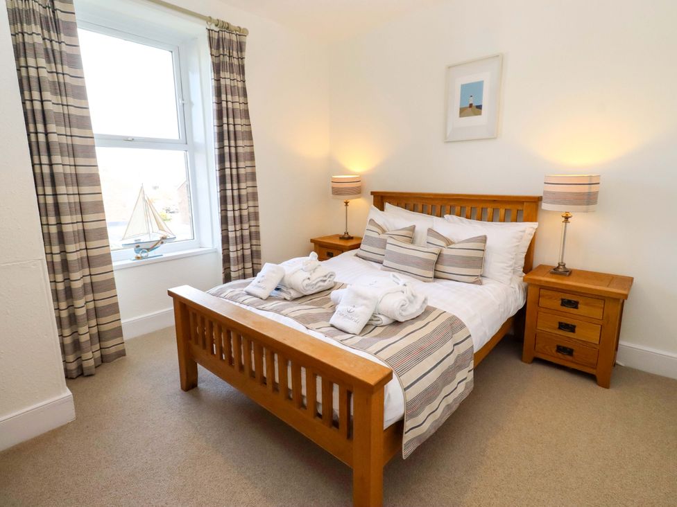 A bedroom with a bed and nightstands at Dinguardi in Seahouses