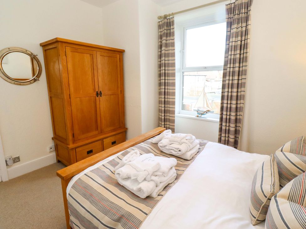 A bedroom with a bed and wardrobe at Dinguardi in Seahouses