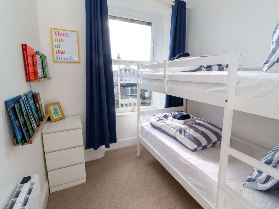 A bedroom with a bunk bed and bookshelf at Dinguardi in Seahouses