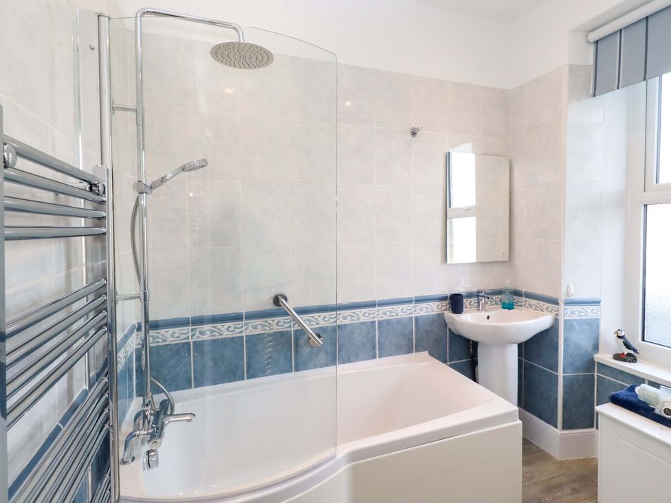A bathroom with a bathtub, shower, sink and towel rail at Dinguardi in Seahouses