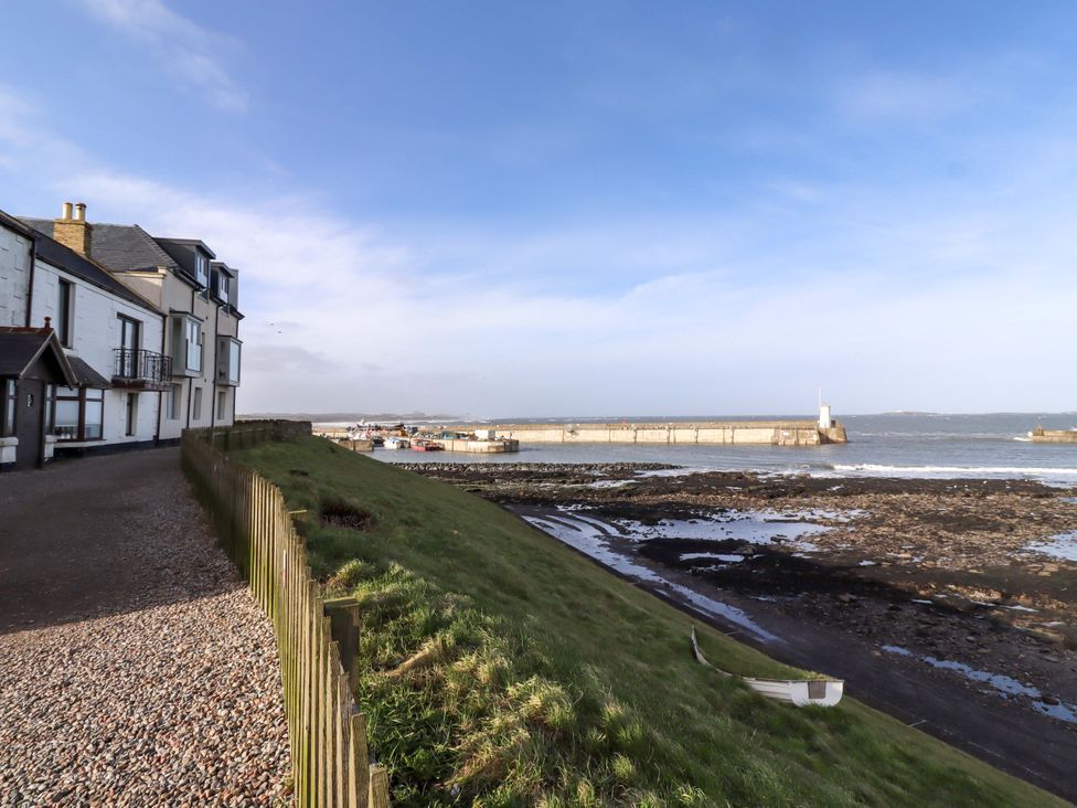 A view of houses and a pier by the sea at Dinguardi in Seahouses