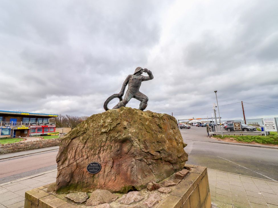 A statue on a rock near a building at Dinguardi in Seahouses