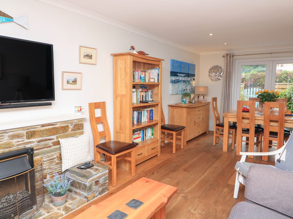 A living room with a bookshelf and dining table at Eydon in Salcombe