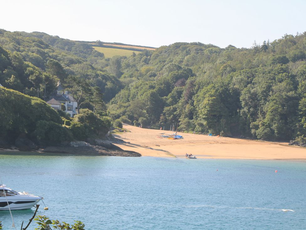 A beach with boats and a house surrounded by trees at Eydon in Salcombe