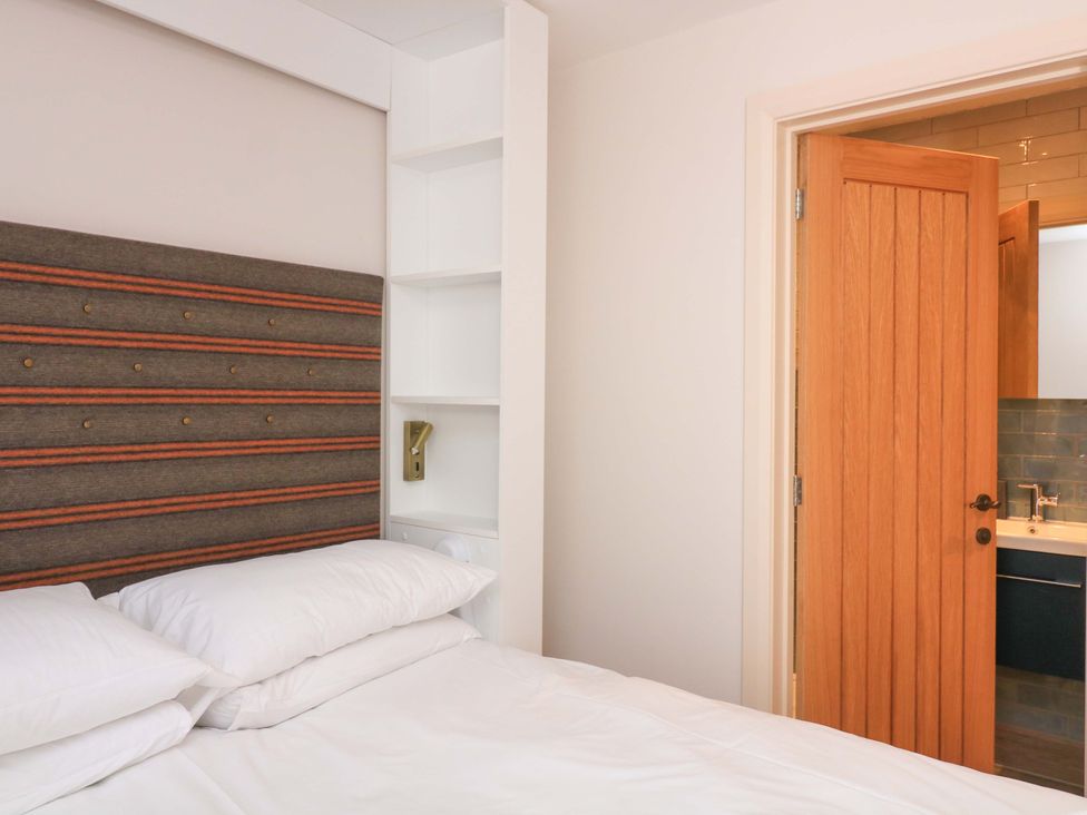 A bedroom with a bed and an open door to a bathroom at Eydon in Salcombe