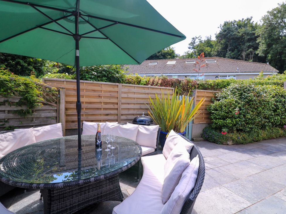 A garden with a table and chairs under an umbrella at Eydon in Salcombe