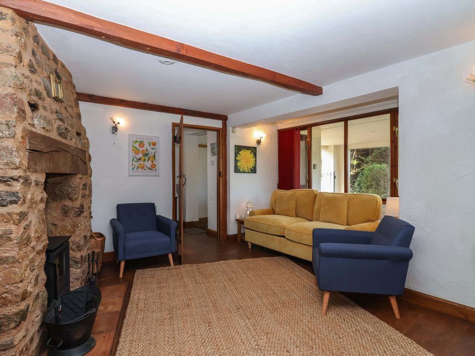 A living room with a stone fireplace and seating area at 1 Eastdon Cottages Exeter