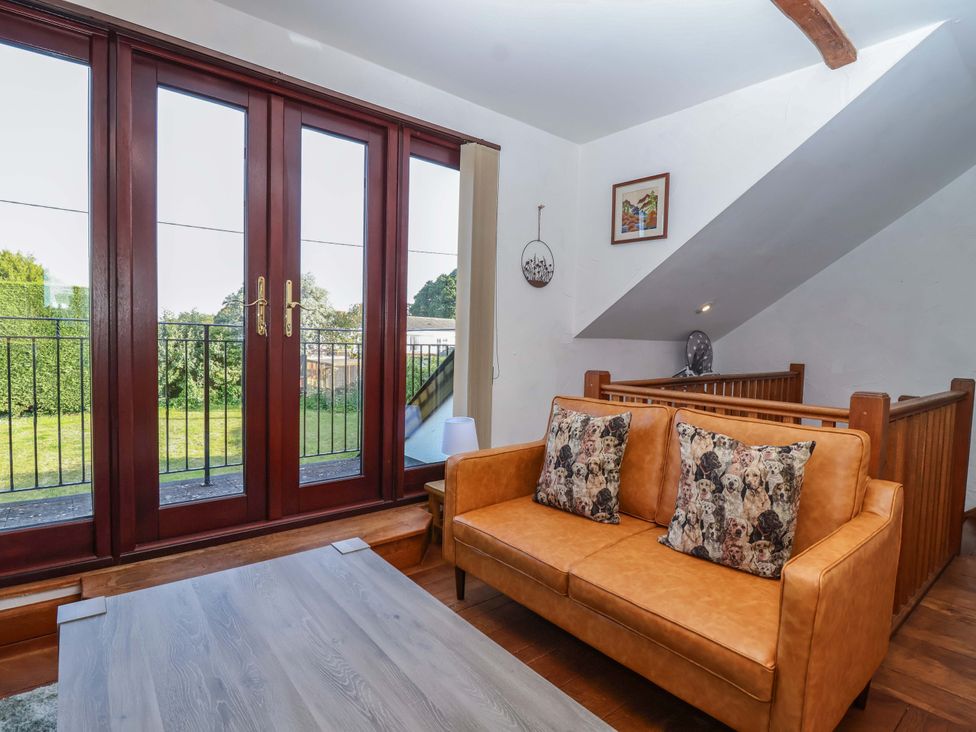 A living room with a sofa and double doors at 1 Eastdon Cottages Exeter