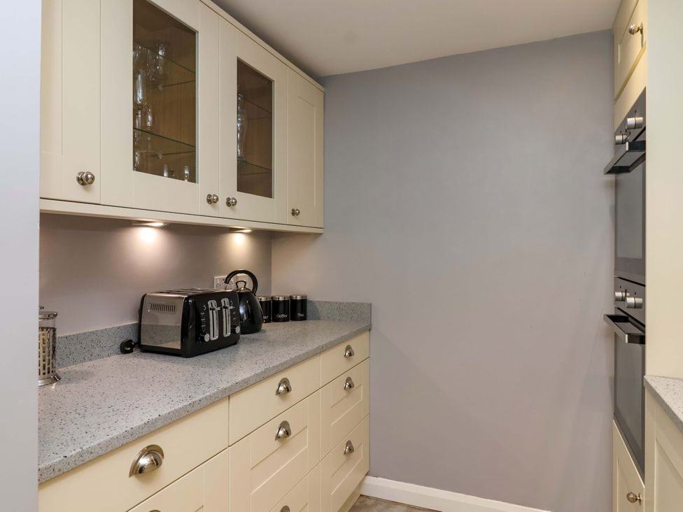 A kitchen with white cupboards and appliances at 1 Eastdon Cottages in Exeter