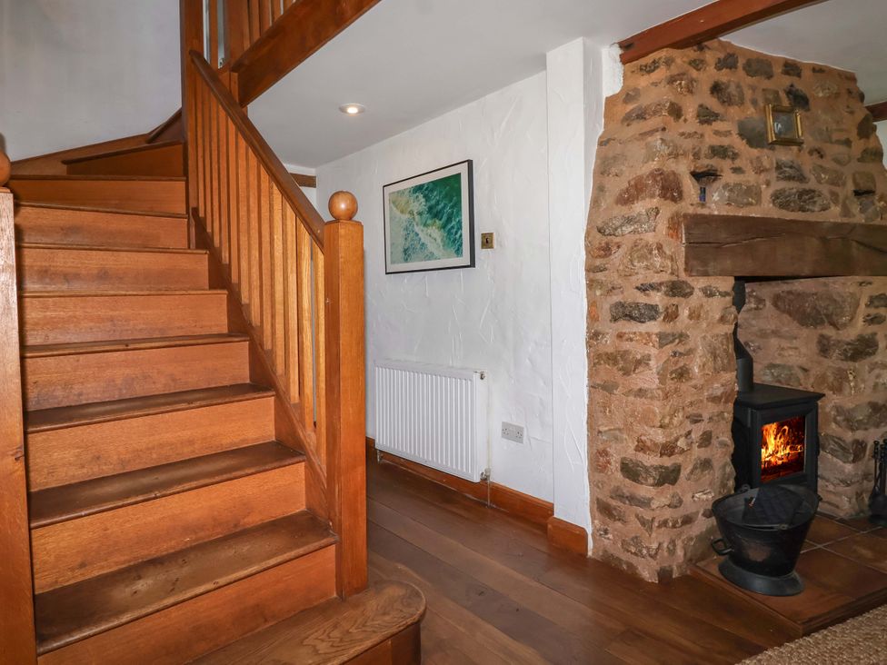 A hallway with stairs and a fireplace at 1 Eastdon Cottages in Exeter