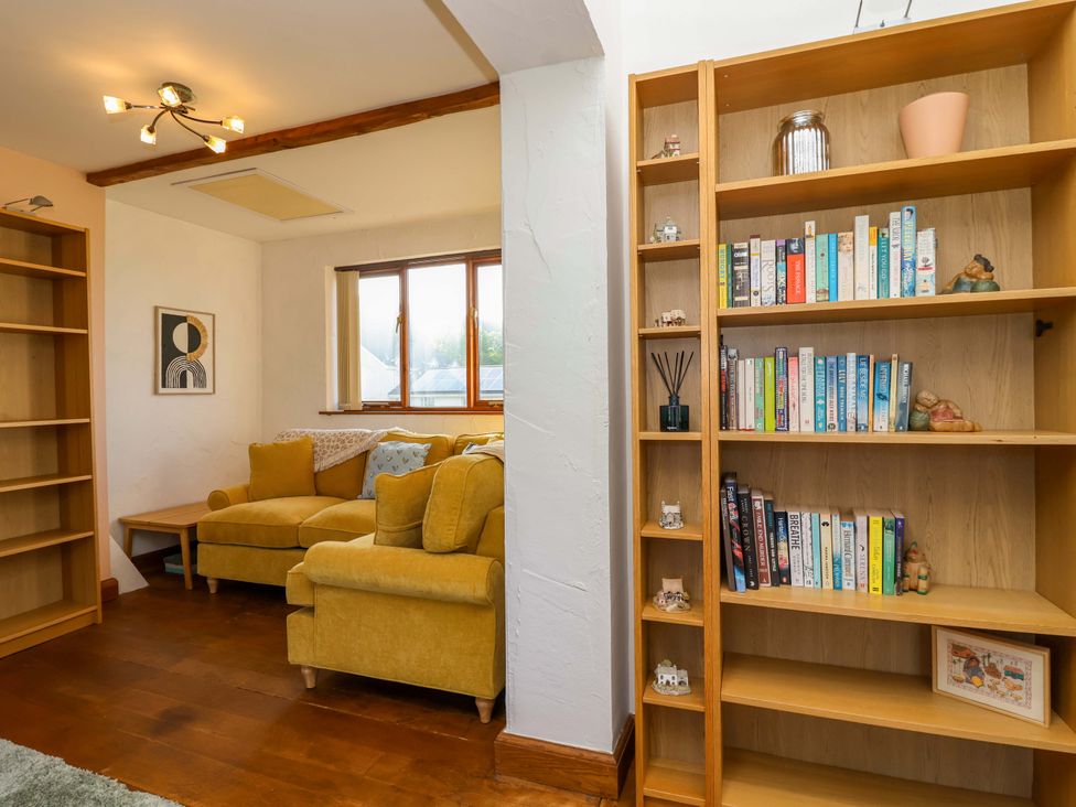A living room with a sofa and bookshelf at 1 Eastdon Cottages in Exeter