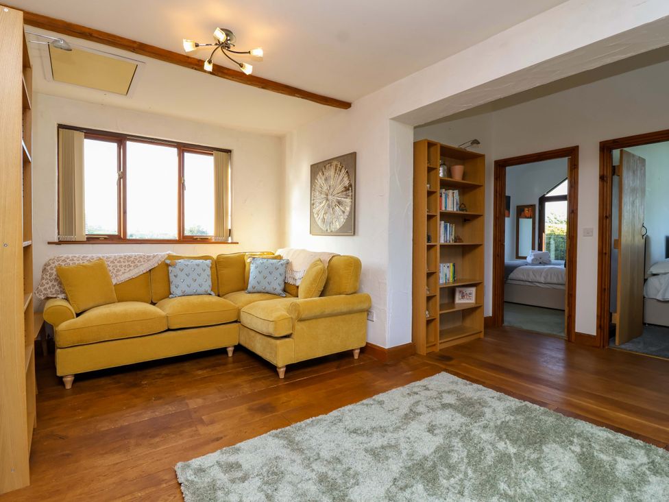 A living room with a sofa and bookshelf at 1 Eastdon Cottages Exeter