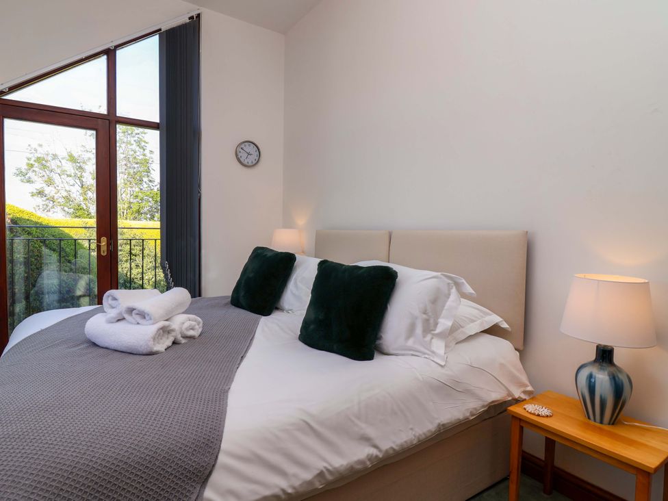 A bedroom with a bed and bedside lamp at 1 Eastdon Cottages in Exeter