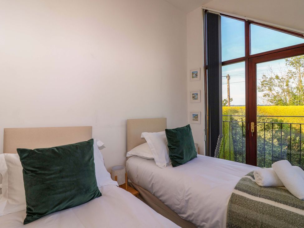 A bedroom with two beds and a window at 1 Eastdon Cottages in Exeter