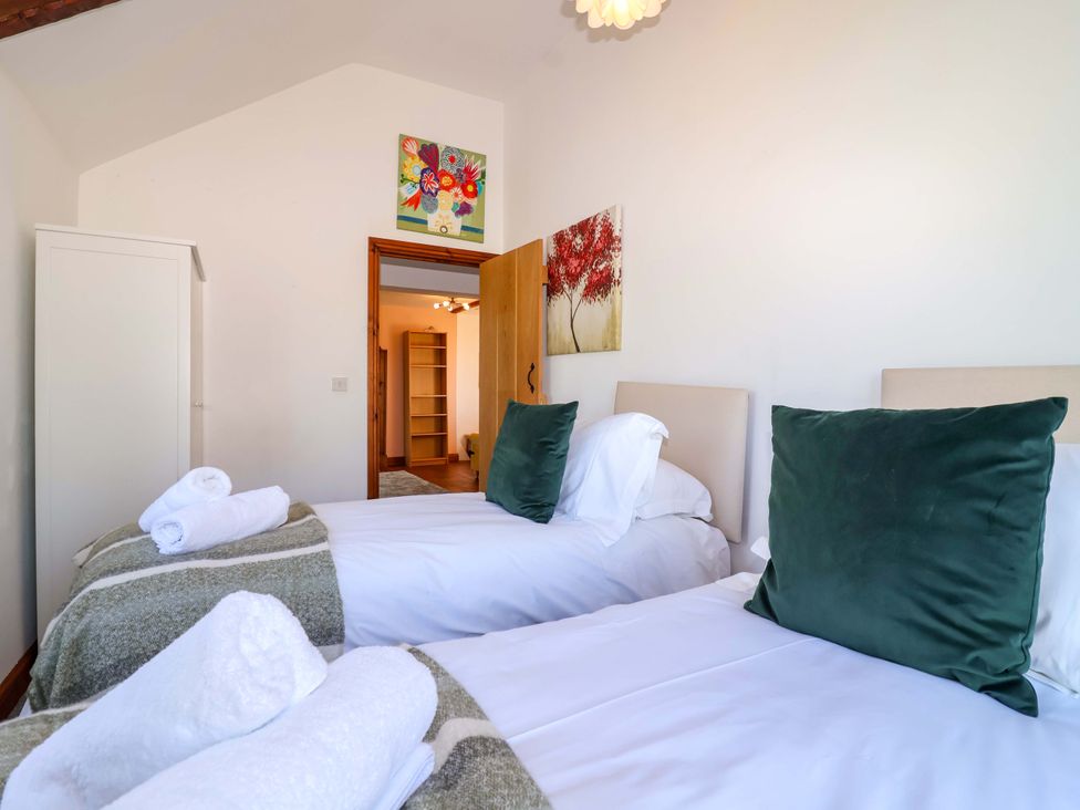 A bedroom with two single beds and a wardrobe at 1 Eastdon Cottages in Exeter