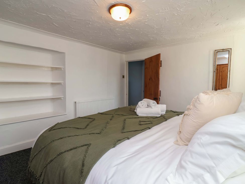 A bedroom with a bed and shelves at 1 Eastdon Cottages in Exeter