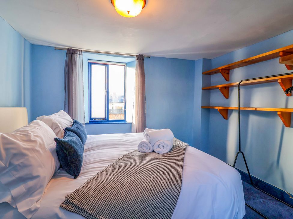 A bedroom with a bed and shelves at 1 Eastdon Cottages in Exeter