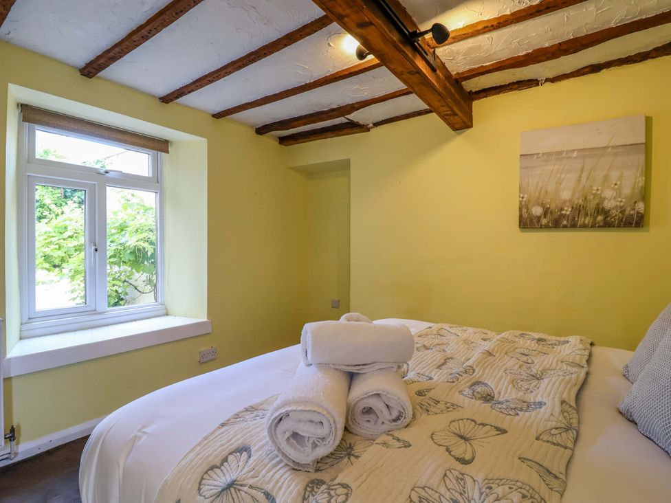 A bedroom with a bed and towels at 1 Eastdon Cottages in Exeter