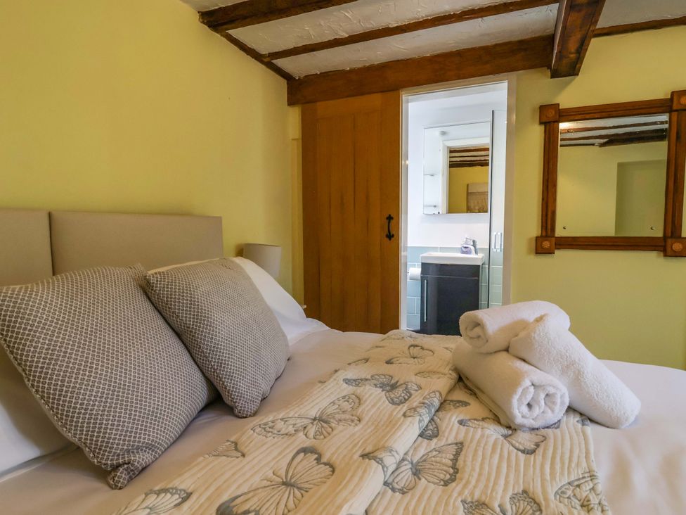 A bedroom with a bed and a door leading to a bathroom at 1 Eastdon Cottages Exeter