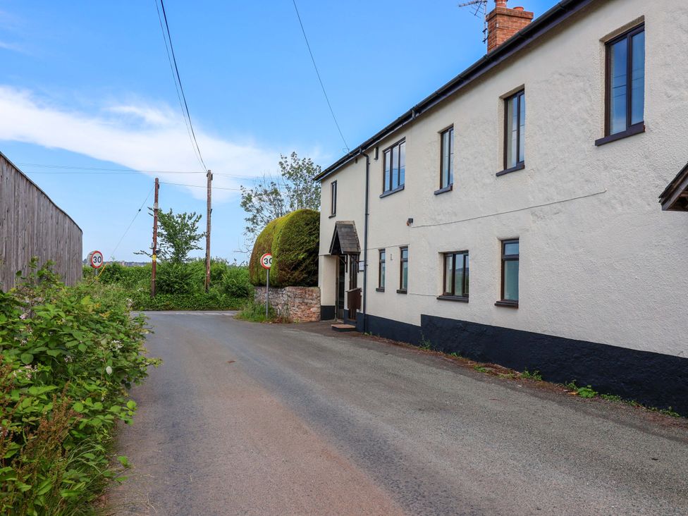 A building along a road with trees and signs at 1 Eastdon Cottages in Exeter