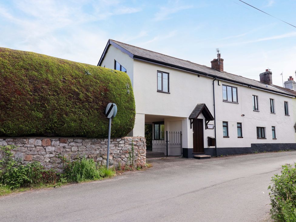 A house with a large bush and stone wall at 1 Eastdon Cottages Exeter