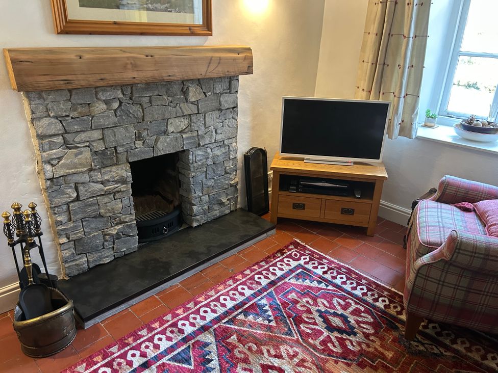 A living room with a fireplace and television at Riverbank Cottage in Beddgelert