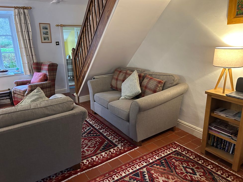 A living room with sofas and an armchair at Riverbank Cottage in Beddgelert