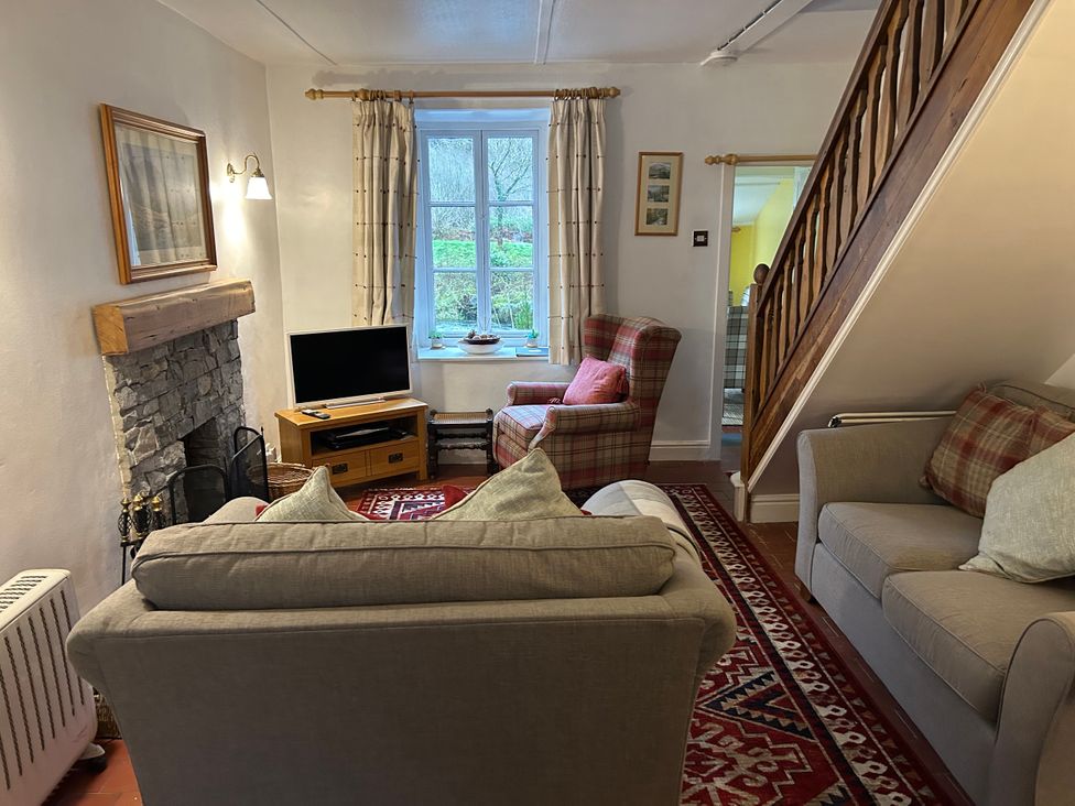 A living room with a sofa and TV at Riverbank Cottage Beddgelert